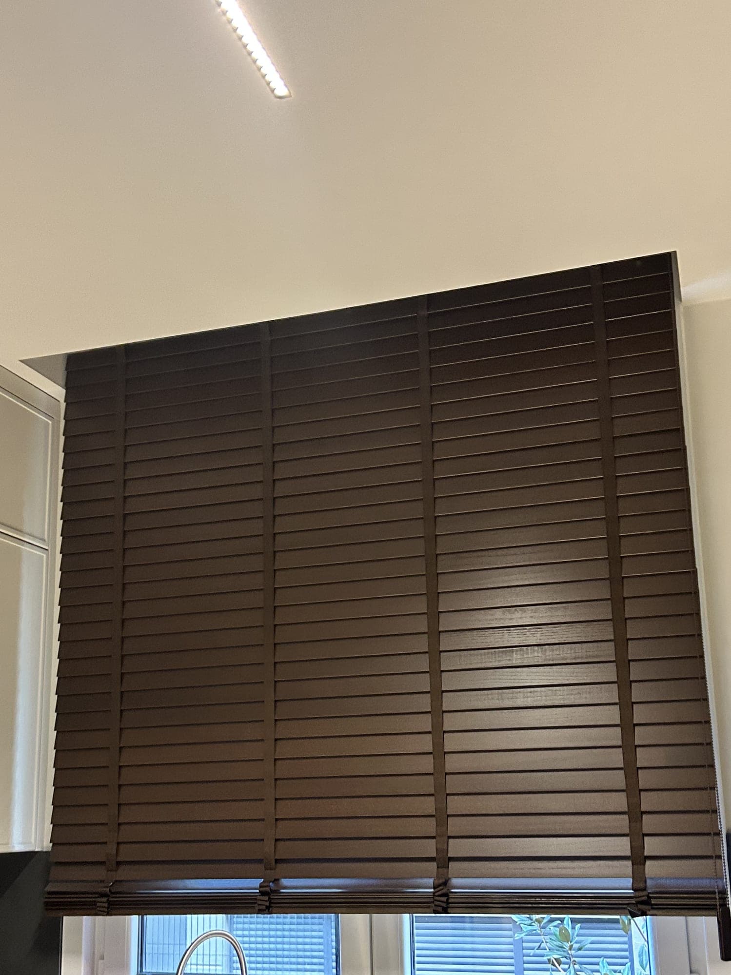 A dark-toned Venetian blind at the kitchen window above the worktop