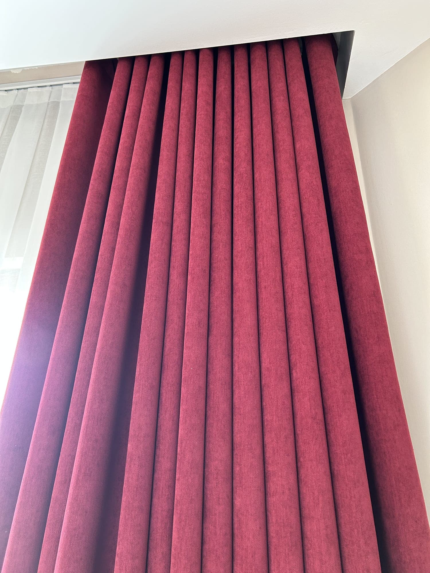 A raspberry drape falling from a recess in the ceiling, close up