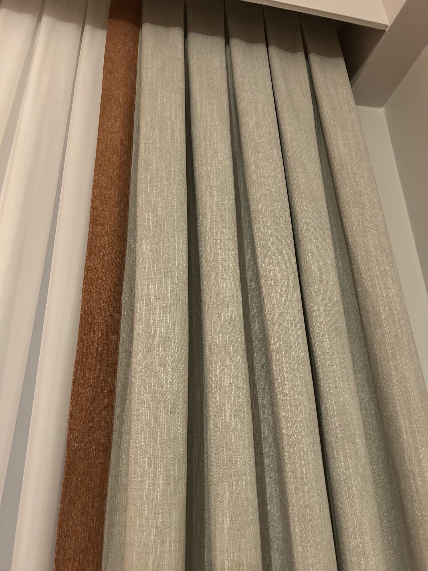 A linen-textured drape with a cinnamon band sewn along its edge, close up