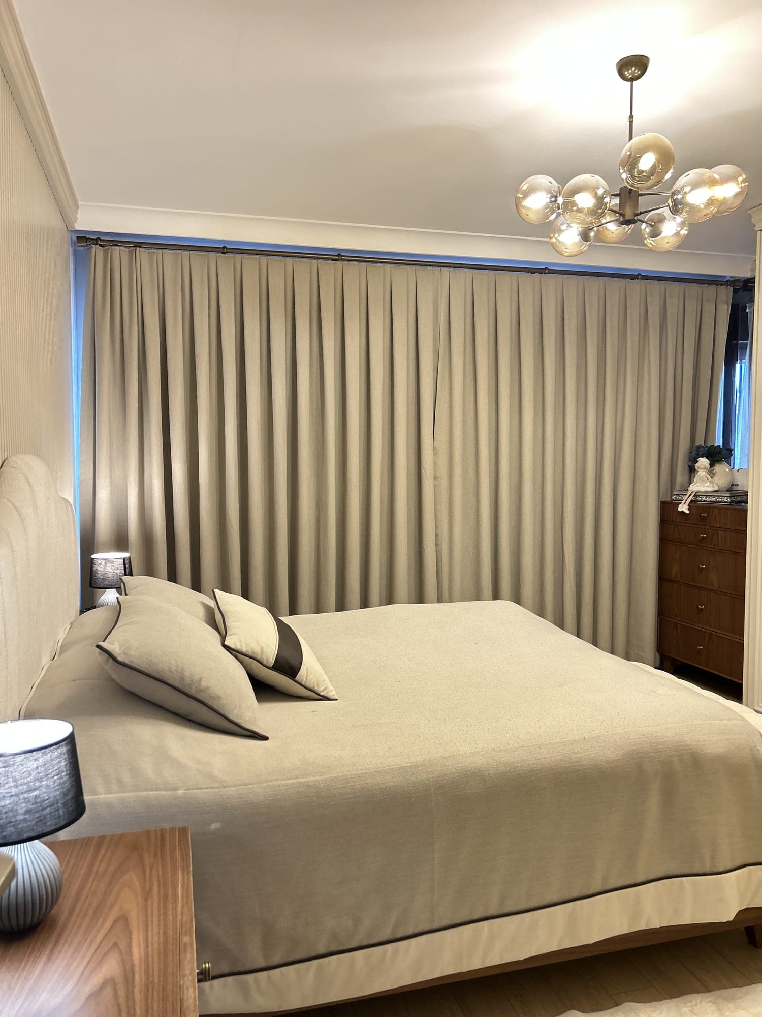 A pleated beige drape covering the whole window in a bedroom