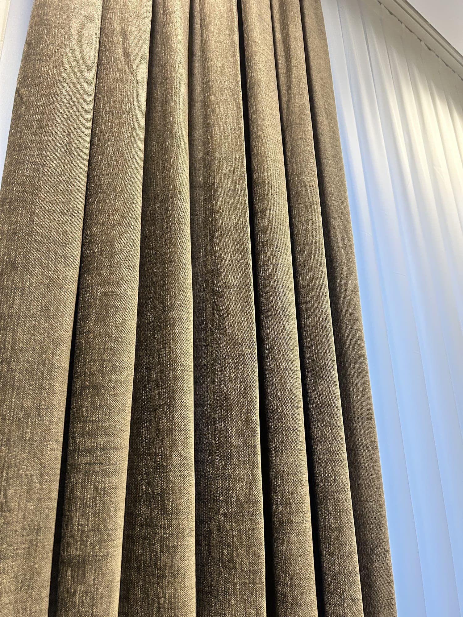 An olive textured drape beside a sheer, close up